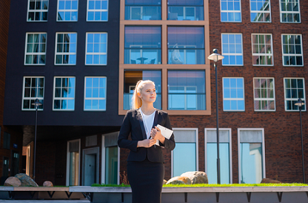 business woman standing outside building holding notebook